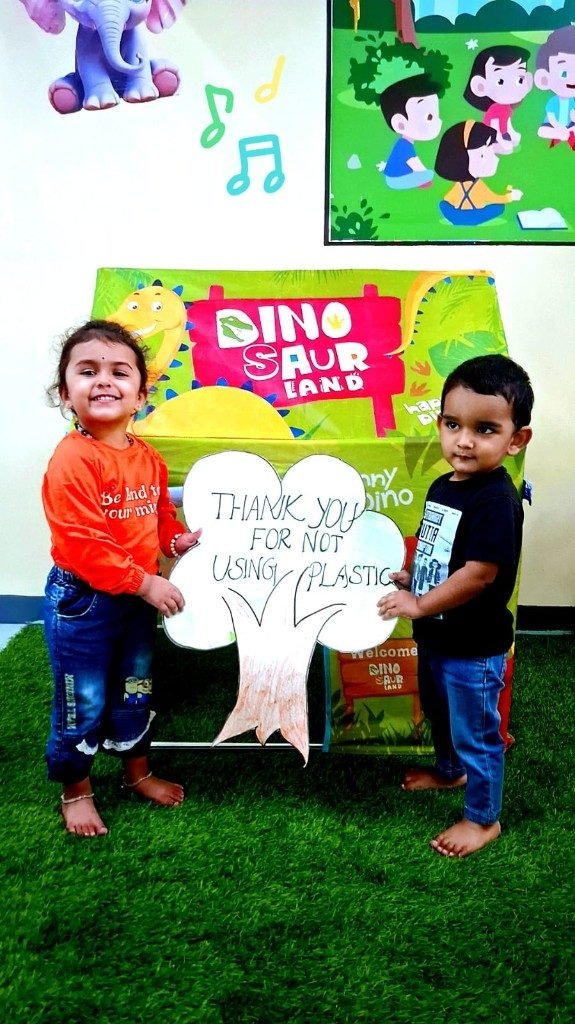 Two toddlers holding a thank you for not using plastic tree sign